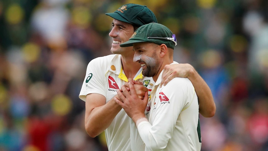 Australia bowlers Pat Cummins and Nathan Lyon embrace during a Test match.