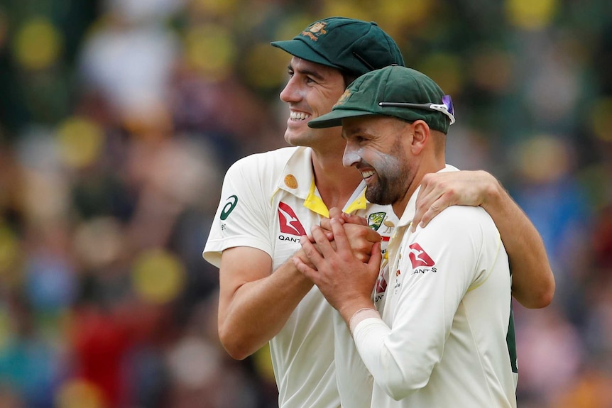Australia bowlers Pat Cummins and Nathan Lyon embrace during a Test match.