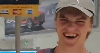 a young man in a cap laughing in an airport