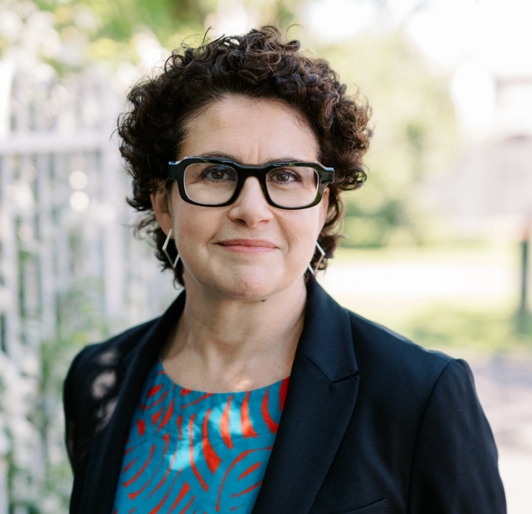 Clare Corbould with short brown curly hair and black rimmed reading glasses