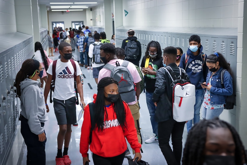 A hallway crowded with masked teens in a school 