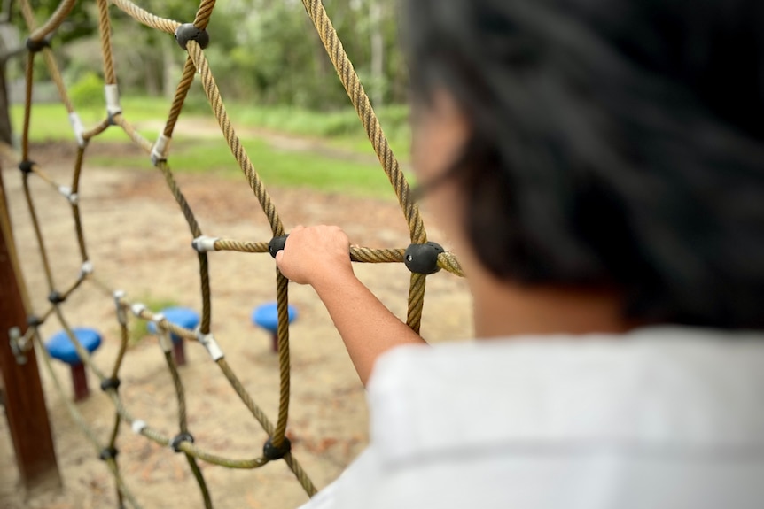 an anonymous photo of a woman turned away from the camera in a children's playground