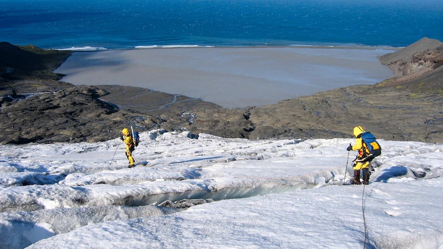 Explorers walk down a snowy slope