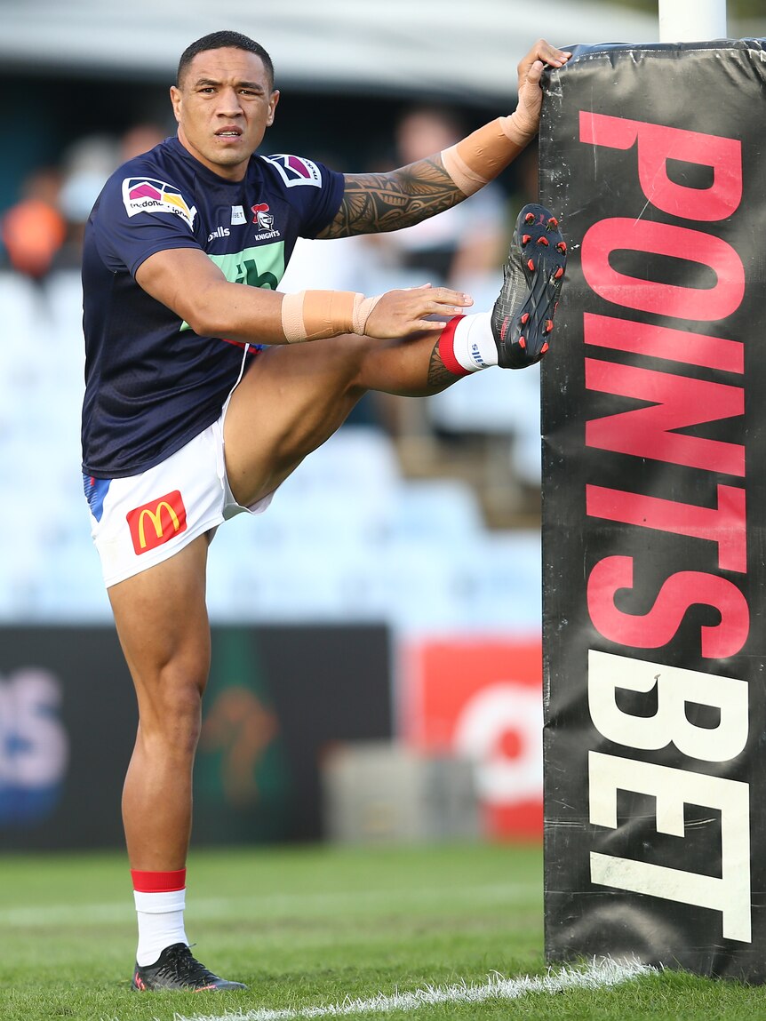A professional rugby league player stretches against a goal post with the words "PointsBet" written on it.