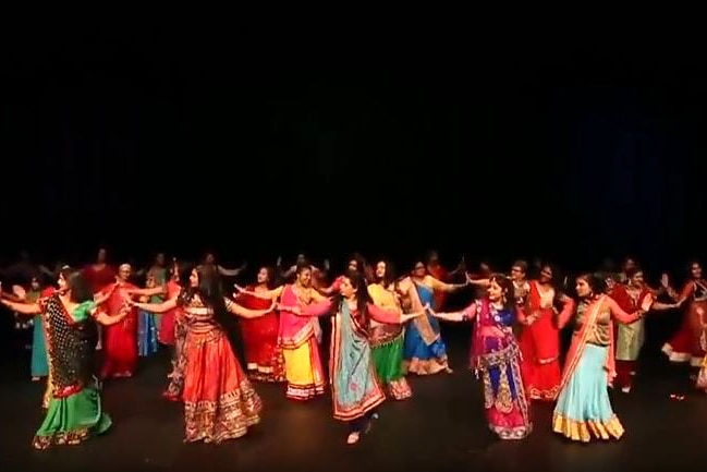 Women in bright colours and traditional Indian and Bhutanese dress dance on stage