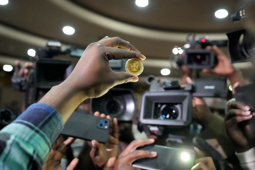 A reserve bank of Zimbabwe offical holds a sample of a gold coin 