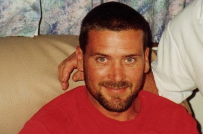 A man sitting on a couch smiling at the camera.