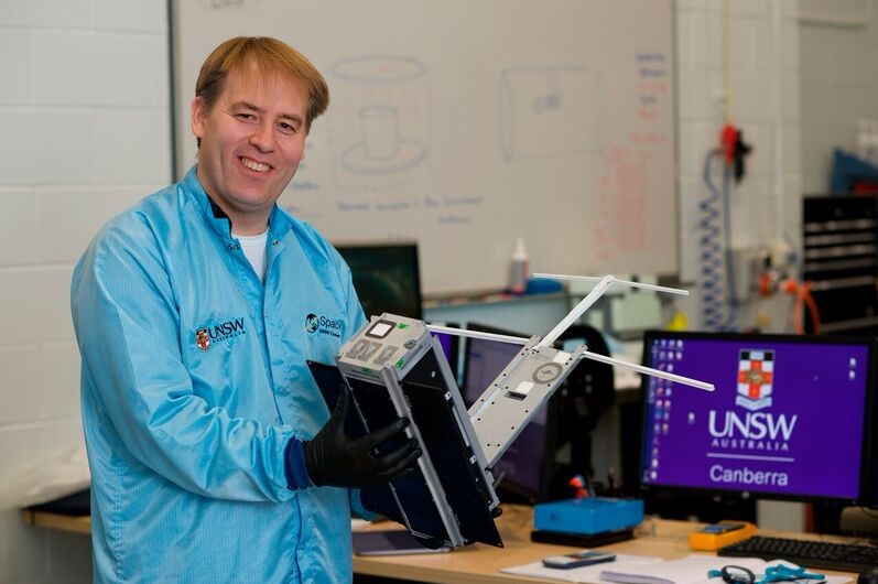 A scientist holds a Cubesat spacecraft