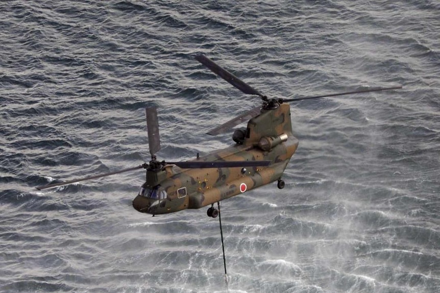 A helicopter collects water from the ocean