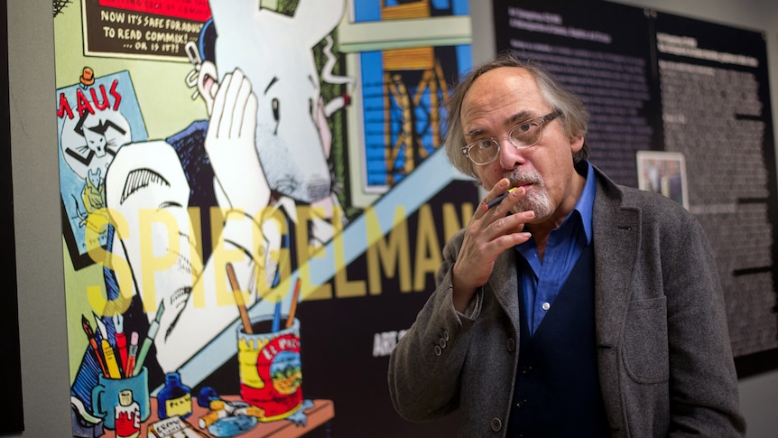 Art Spiegelman poses in front of a poster from his book Maus.