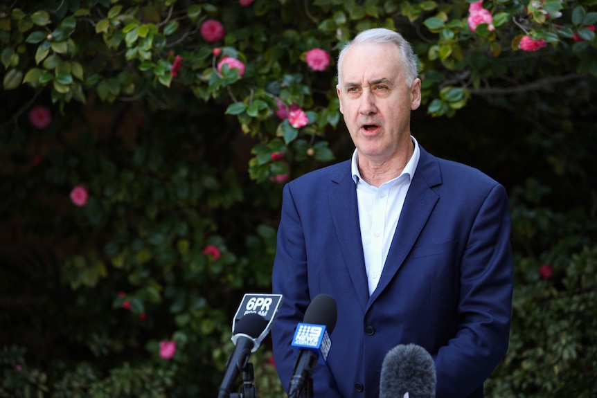 A mid-shot of WA Liberal leader David Honey speaking at a media conference in a garden with microphones in front of him.