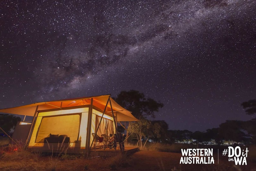 A tent is lit up under the Milky Way stars.