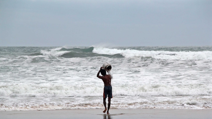 A man performs a ritual for safety ahead of cyclone Hudhud