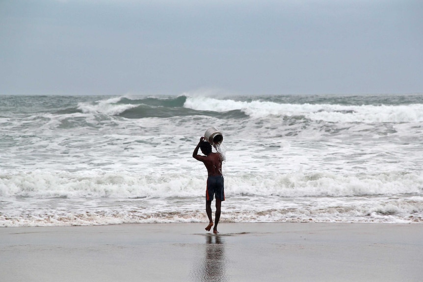 A man performs a ritual for safety ahead of cyclone Hudhud
