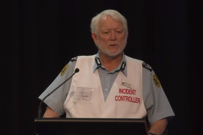 An older man wearing a blue shirt and a white incident controller vest