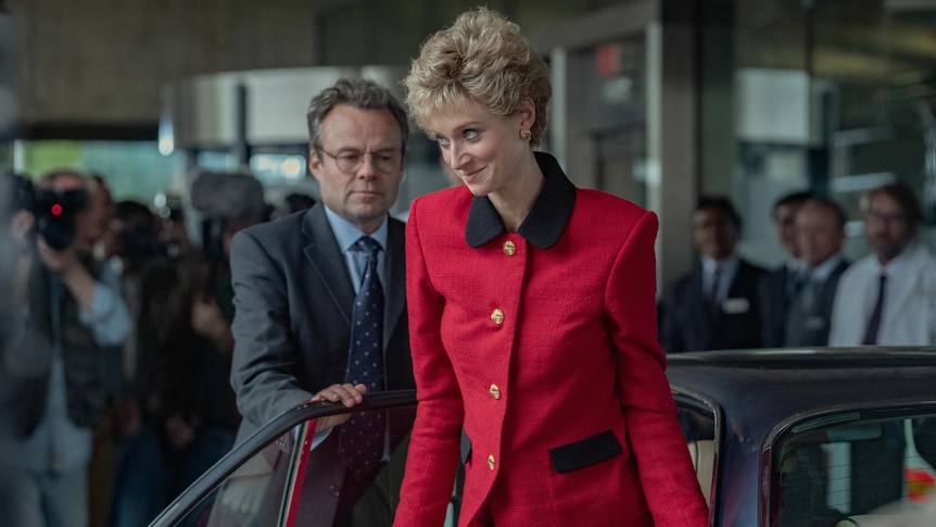 Diana steps out of a car in a red coat.