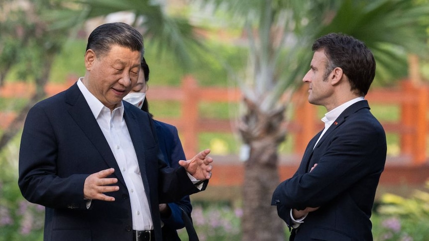 Presdients Xi Jinping ( China ) and Emanuel Macron ( france) stand and talk in a garden 