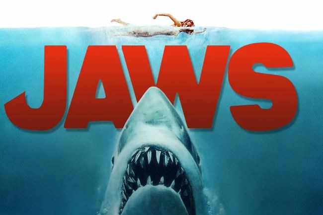 An image of a gigantic shark under a swimmer and the word JAWS.