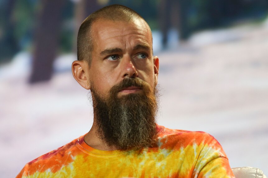 A man with a shaved head a long scraggly beard and a tie-dye t-shirt