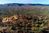 A woman scans the MacDonnell Ranges while walking the Larapinta Trail.