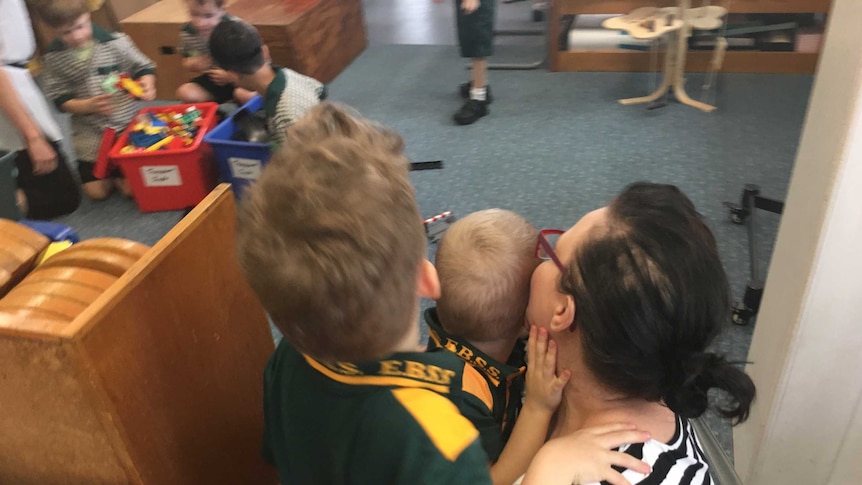 Boys stand with their mum in the classroom.