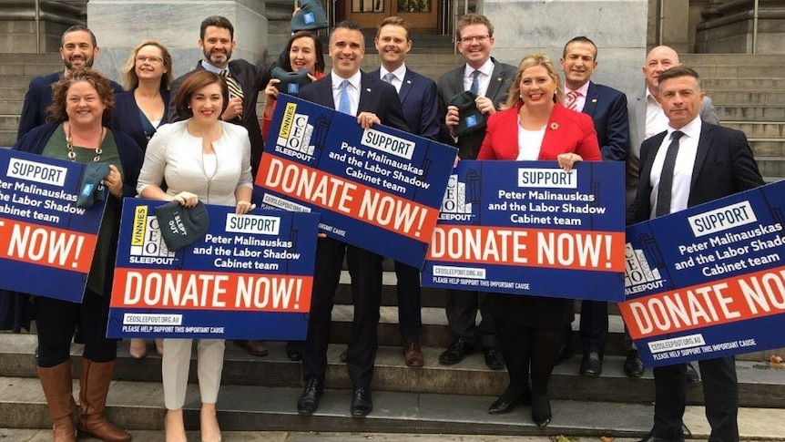 A group of people holding signs in front of SA Parliament House