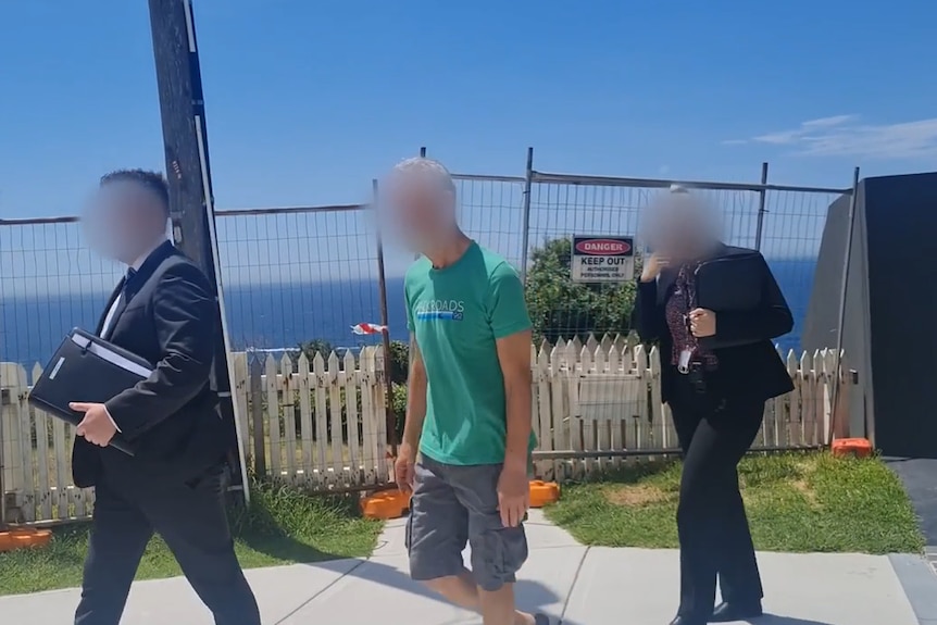 Two police officers and one man walking out of a house near the beach with all their faces blurred