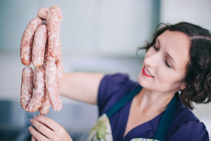 chrissy flanagean inspecting a string of sausages