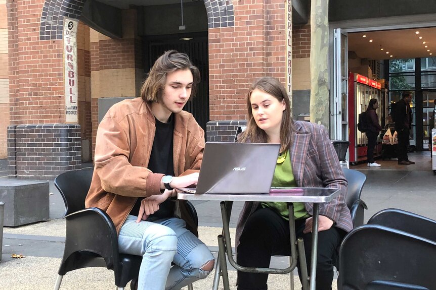 University of Technology Sydney students Kristo and Lily sit at an outdoor table with a laptop