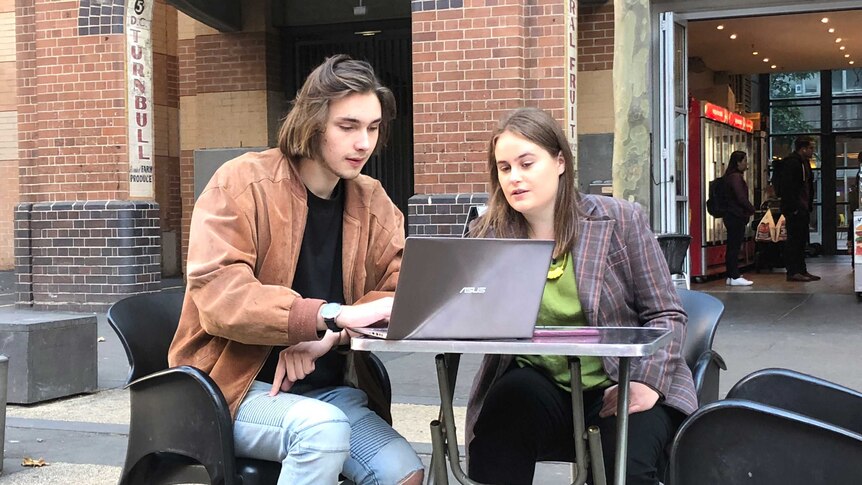 University of Technology Sydney students Kristo and Lily sit at an outdoor table with a laptop