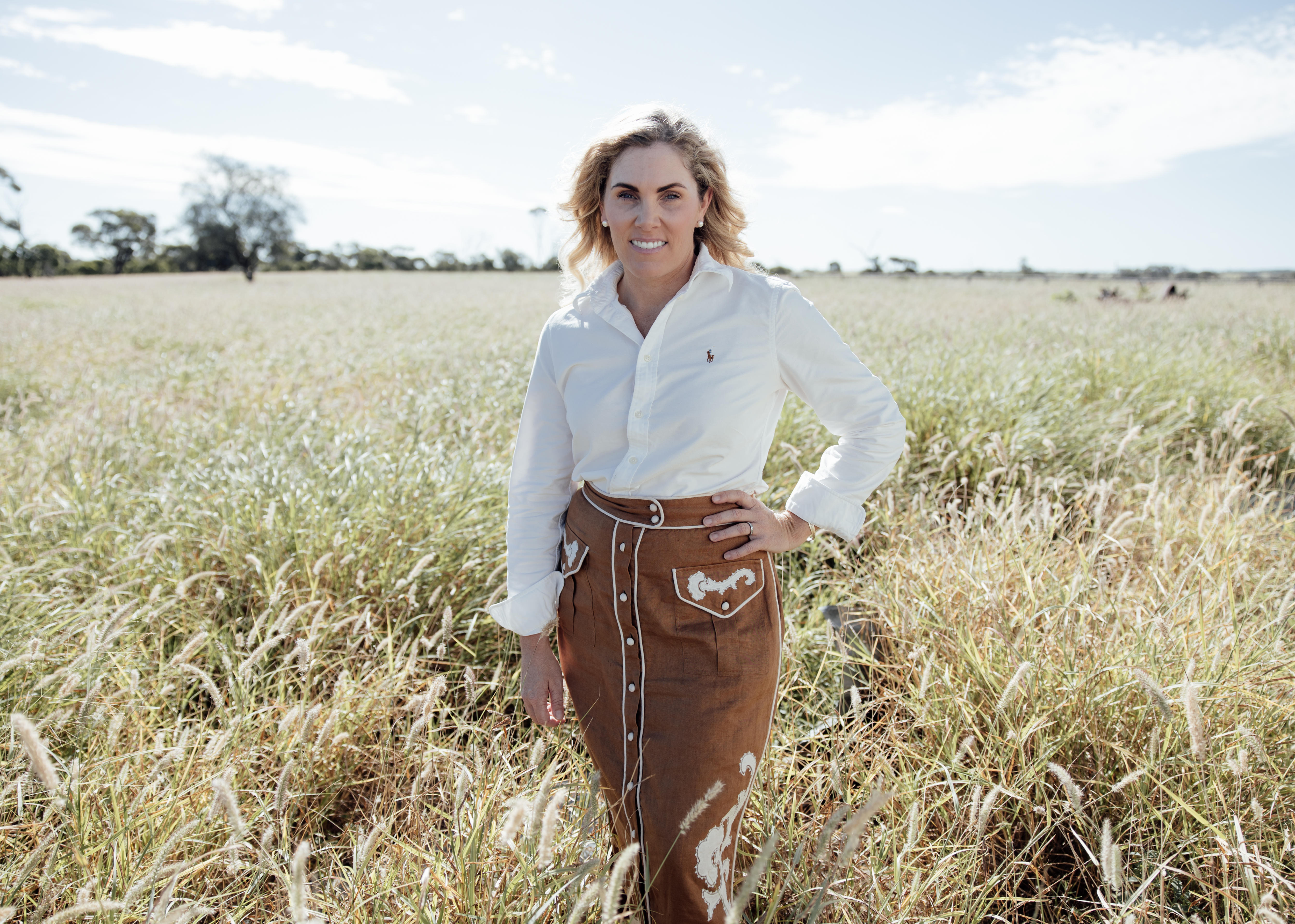 A woman wearing a white shirt and brown skirt standing in a field