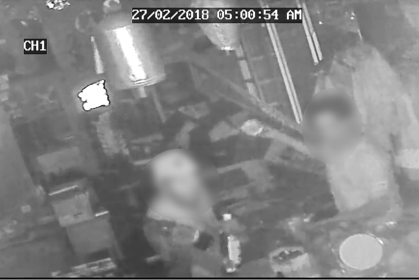 CCTV footage depicts the blurred faces of two men inside the Nightcliff cafe holding liquor bottles.