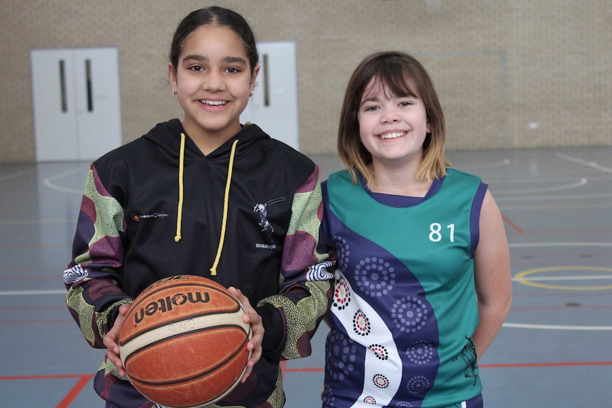 Two young girls in active wear on sports court.