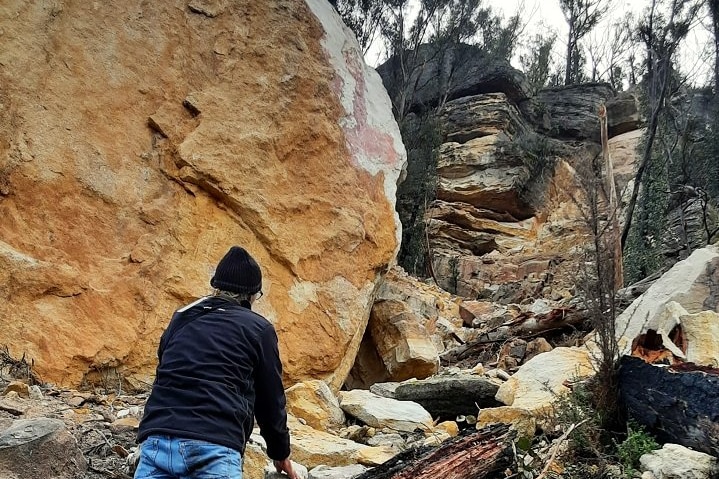 person looking at sandstone cliff collapsed
