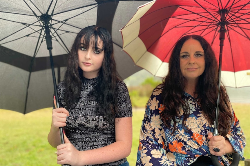 Deux femmes sont assises sous des parapluies sous la pluie.