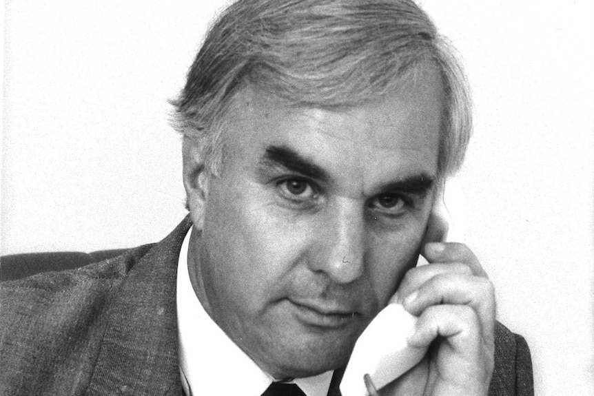 Black and white picture of Keith in a suit holding an old telephone