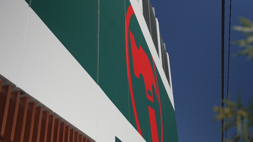 A red hammer in a circle on a green background on the side of a building.