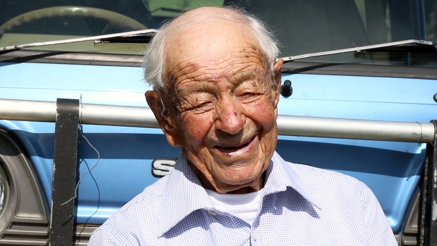 Close up of elderly man sitting in front of blue van
