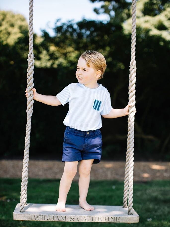 Prince George stands on a swing