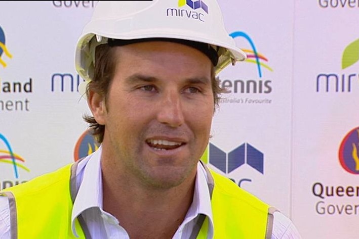 A man with short, brown hair wearing a white hardhat an d a yellow high-vis vest