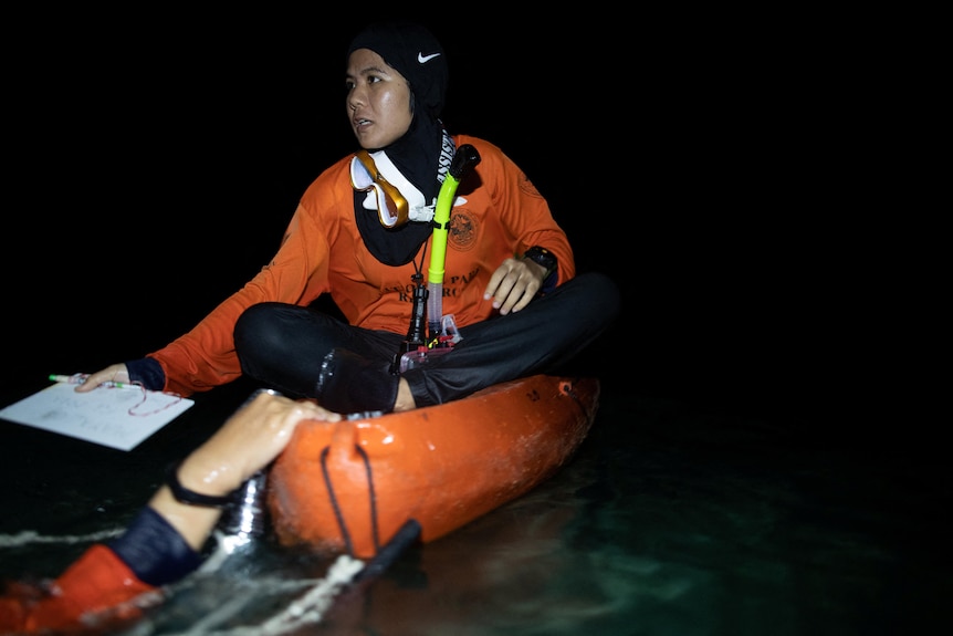 A woman sitting in a kayak at night