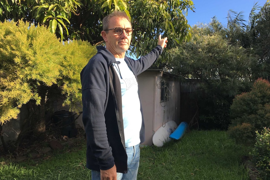 A man in a backyard pointing in the direction of the jail.