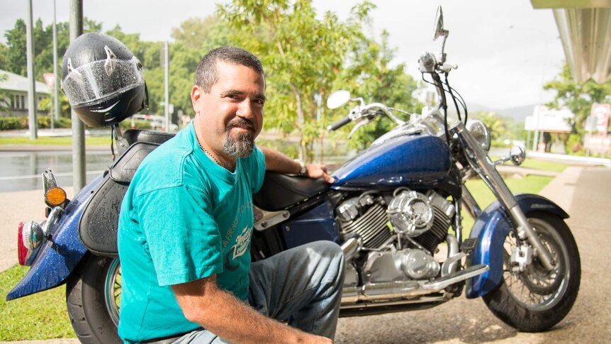 Steve Cutuli kneels beside the motorcycle he'll be riding in the 2016 motorcycle muster.