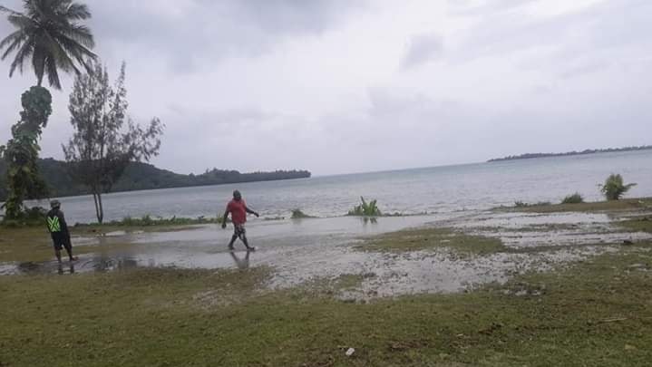 Two man stand in a puddle caused by small tsunami waves in Vanuatu.