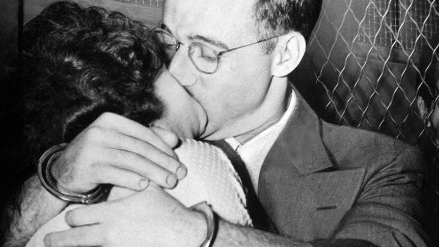 Black and white image of Julius Rosenberg and his wife Ethel kissing while handcuffed.