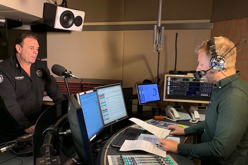 John Setka stands in a radio studio opposite Hamish Macdonald, who refers to notes as he asks a question.