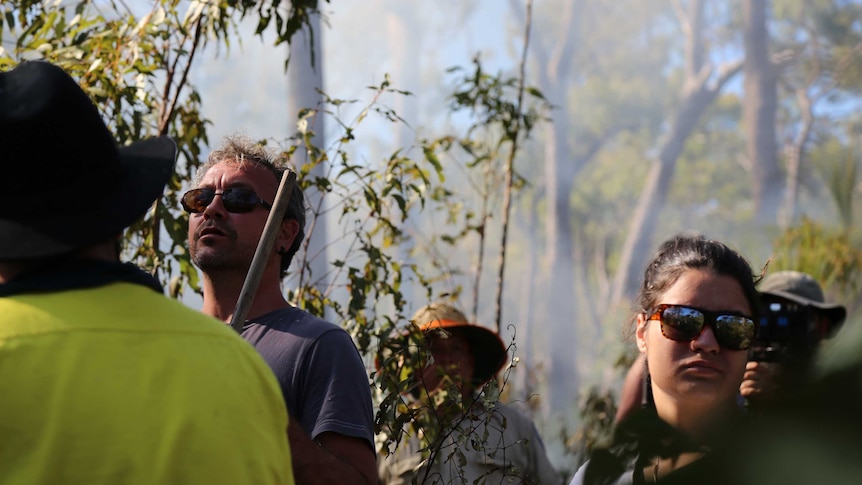 A man oversees a traditional burn on country in Cape York, with smoke haze obscuring the scenery