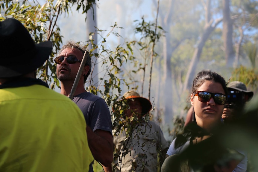 A man oversees a traditional burn on country in Cape York, with smoke haze obscuring the scenery