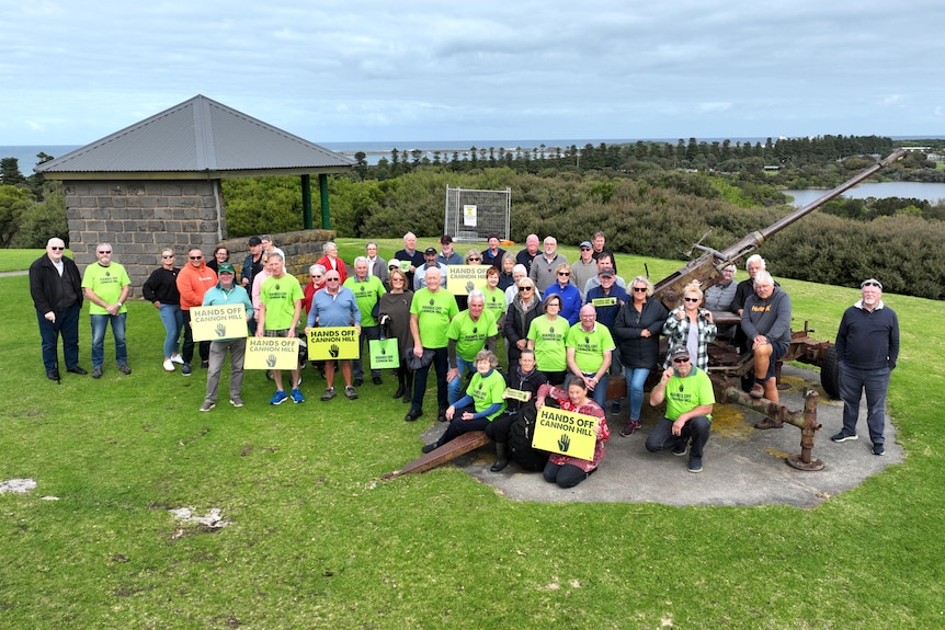A large group of protesters with placards and sitting on top of a hill in Warrnambool.