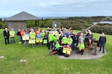 A large group of protesters with placards and sitting on top of a hill in Warrnambool.